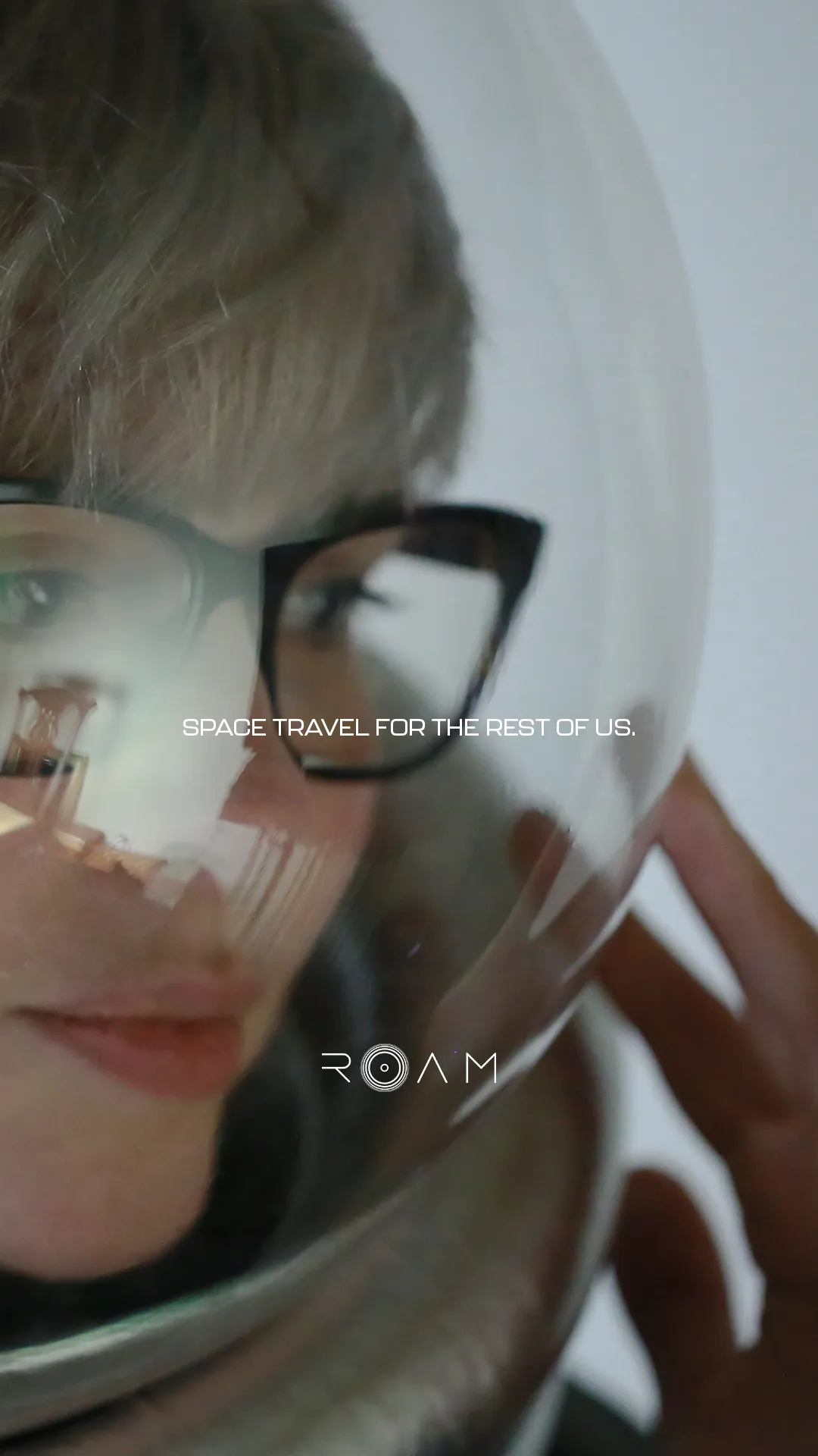 Close-up of a person wearing glasses and a space helmet with the text 'Space travel for the rest of us' and the ROAM logo.