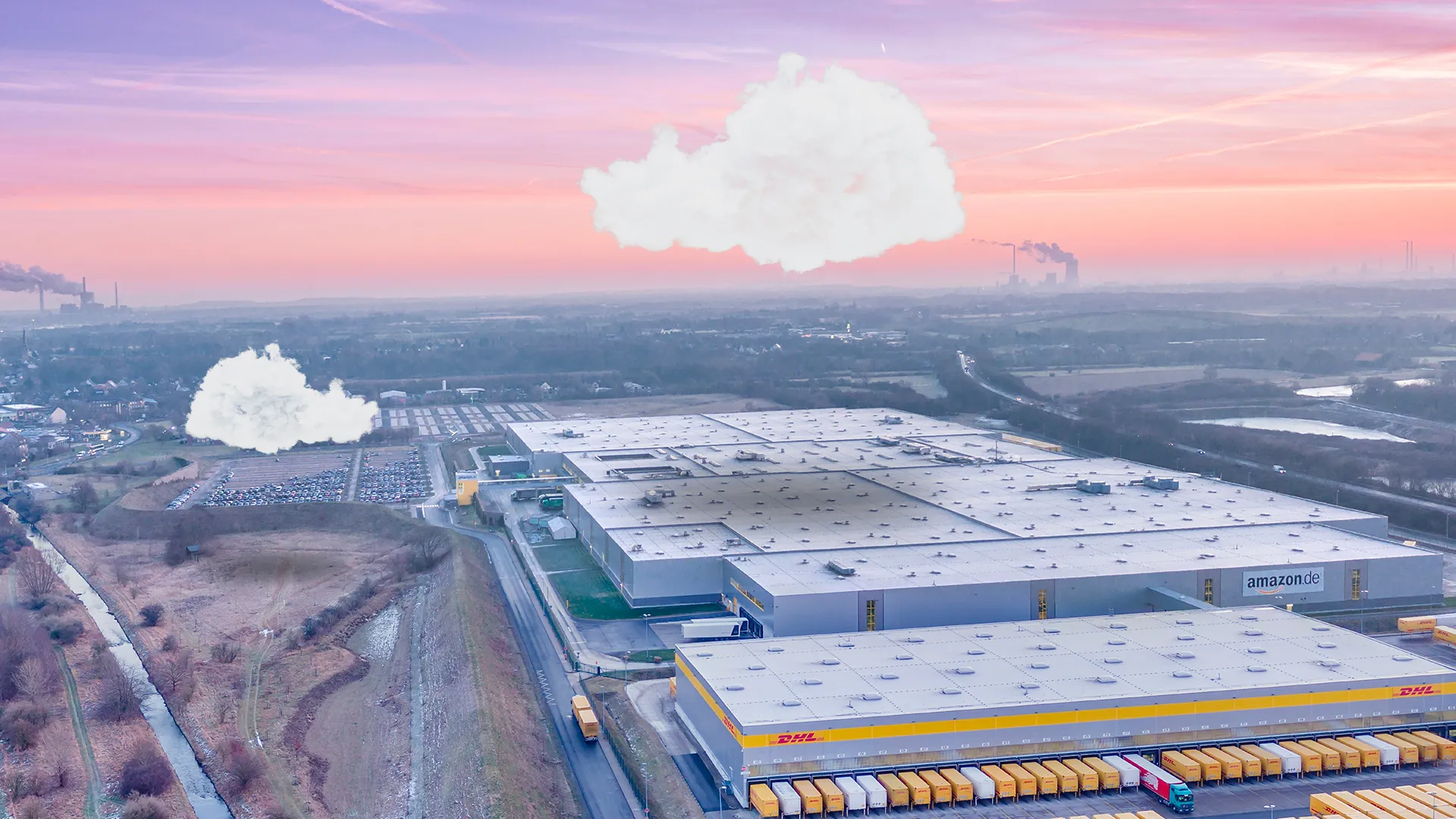 Aerial view of Amazon and DHL warehouses with a sunset sky and clouds above an industrial landscape.