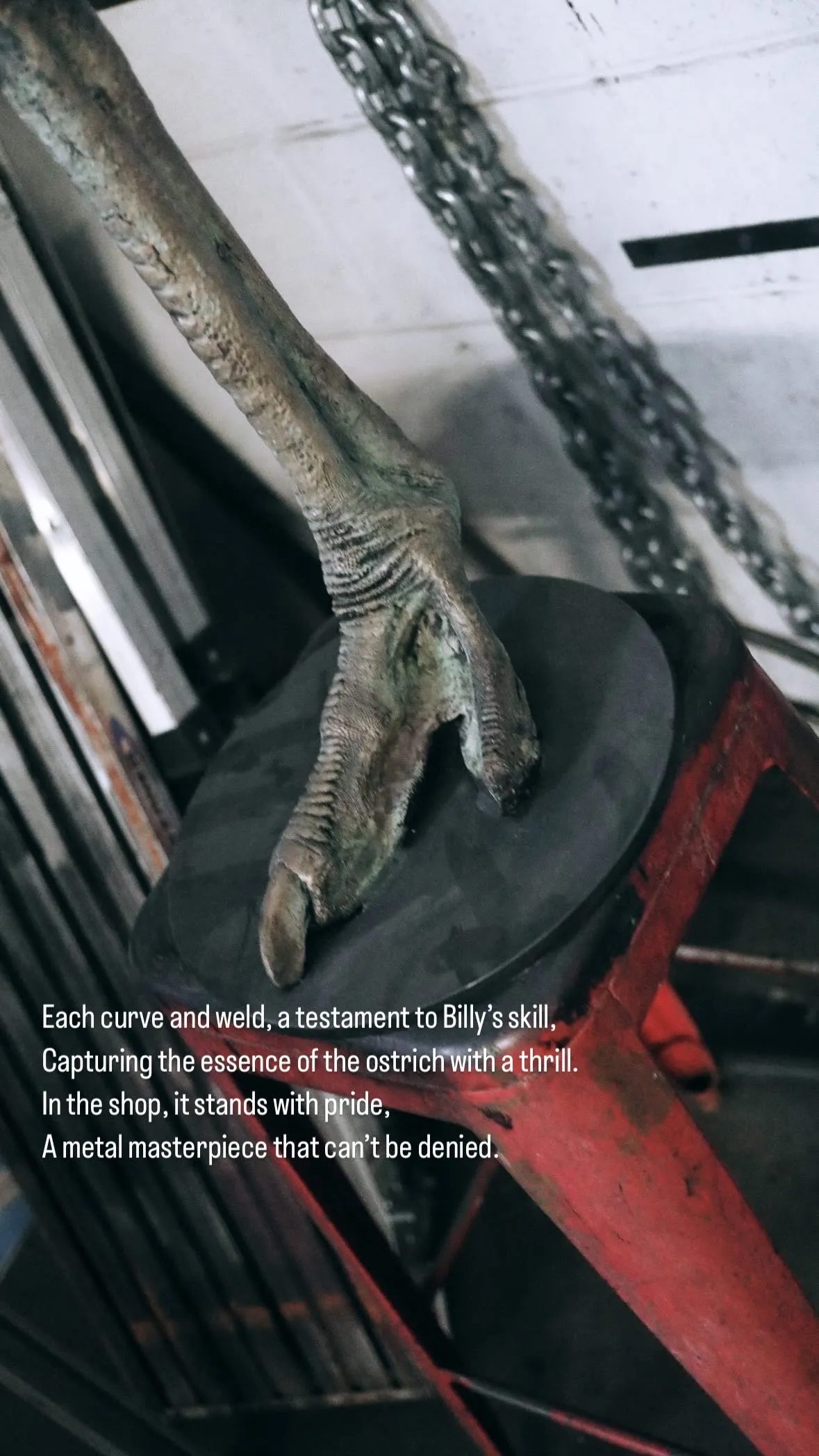 Close-up of a detailed metal sculpture of an ostrich foot standing on a round black platform in a workshop.